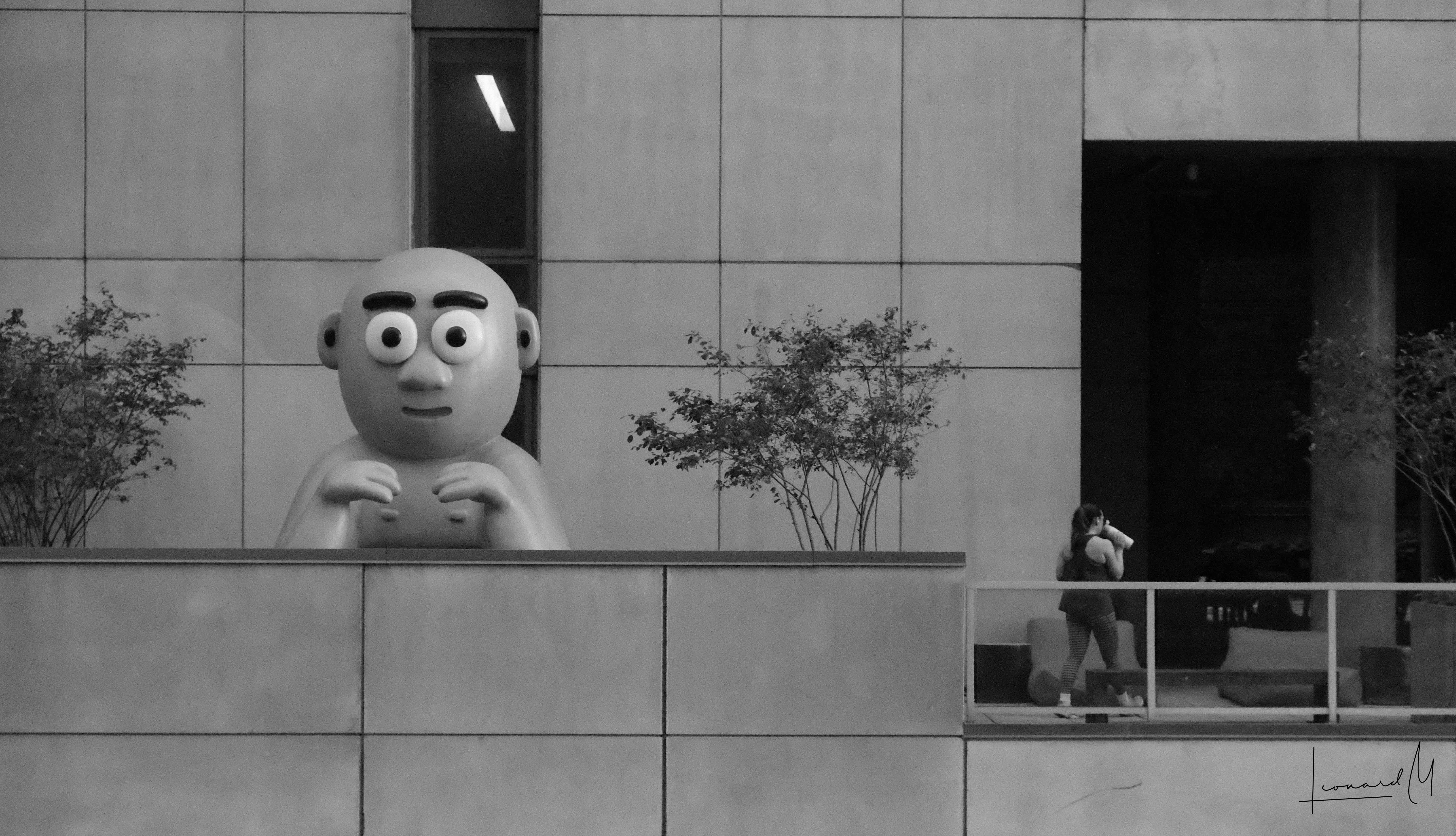 A silly statue and a woman walking away from it